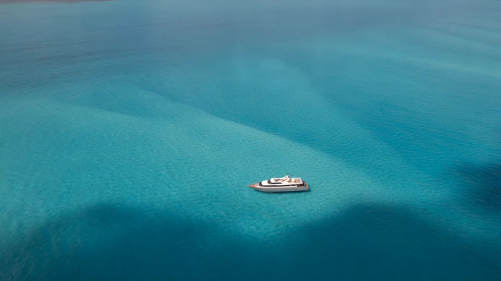 Vista aérea del yate Avalon de 115 pies sobre aguas turquesa en calma.