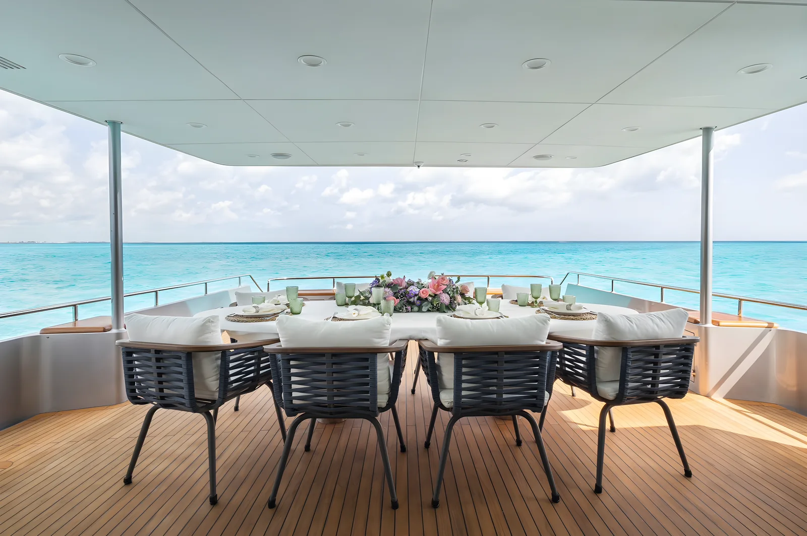 Comedor exterior en la cubierta de popa del yate Avalon 115ft con mesa dispuesta y vista al mar.