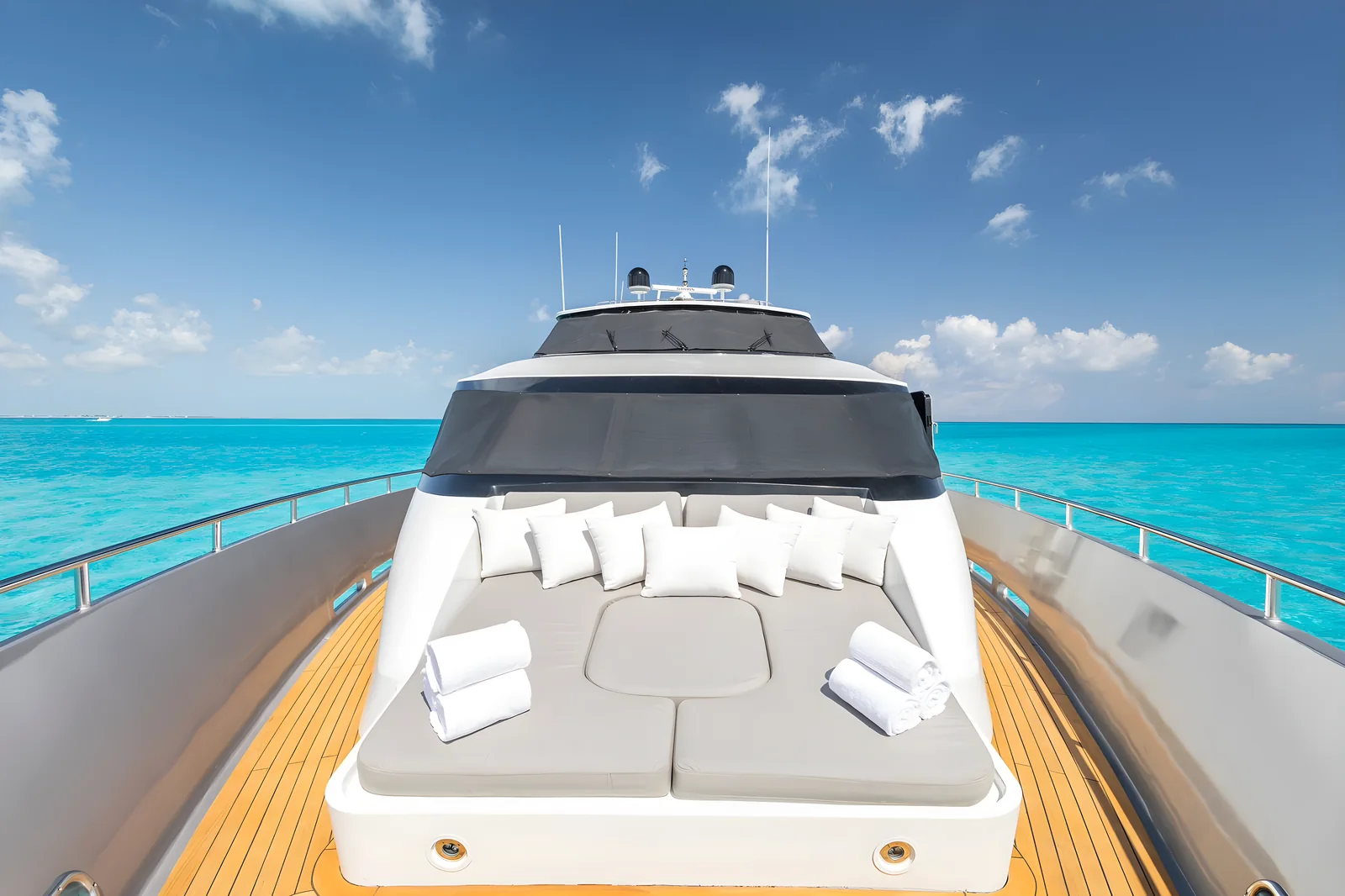 Cama solar en la proa del yate Avalon 115ft con cojines blancos y toallas.