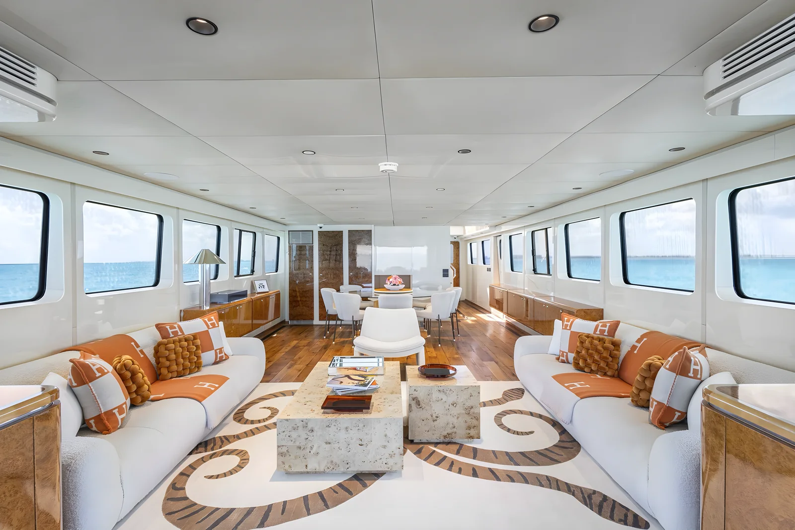 Espacioso salón del yate Avalon de 115 pies con sofás, mesa de centro y comedor al fondo.