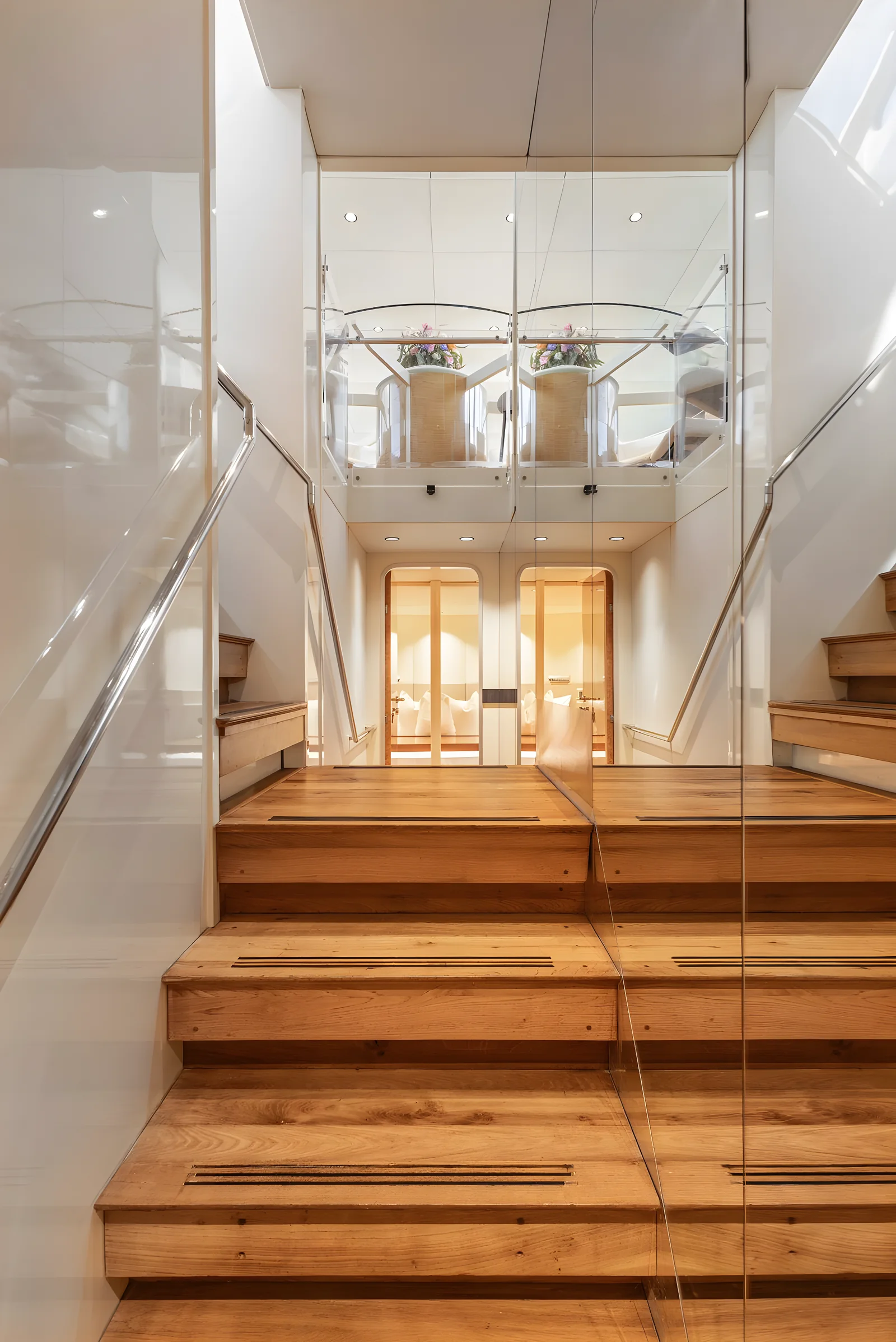 Escalera interior del yate Avalon con peldaños de madera y paneles de cristal.