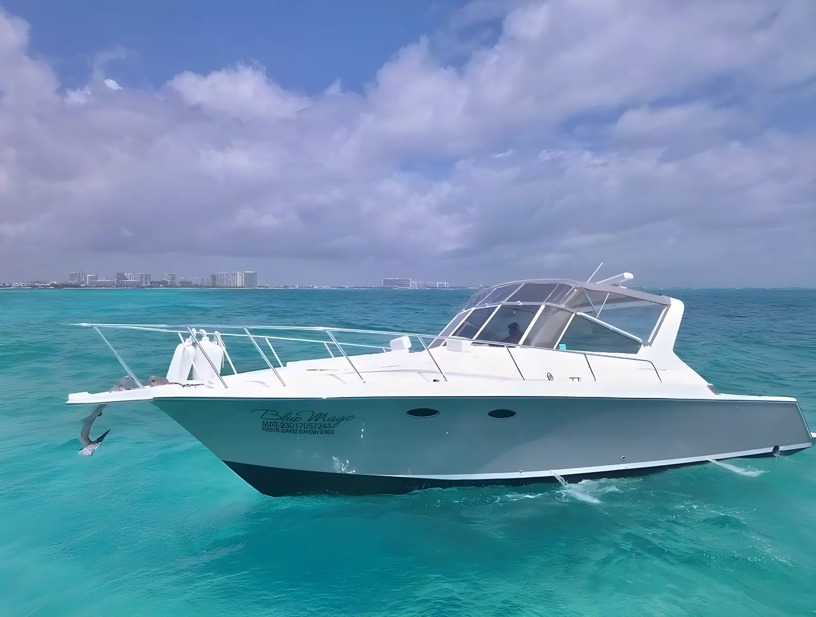 Perfil lateral del yate Blue Magic de 38 pies en aguas turquesa con la costa al fondo.