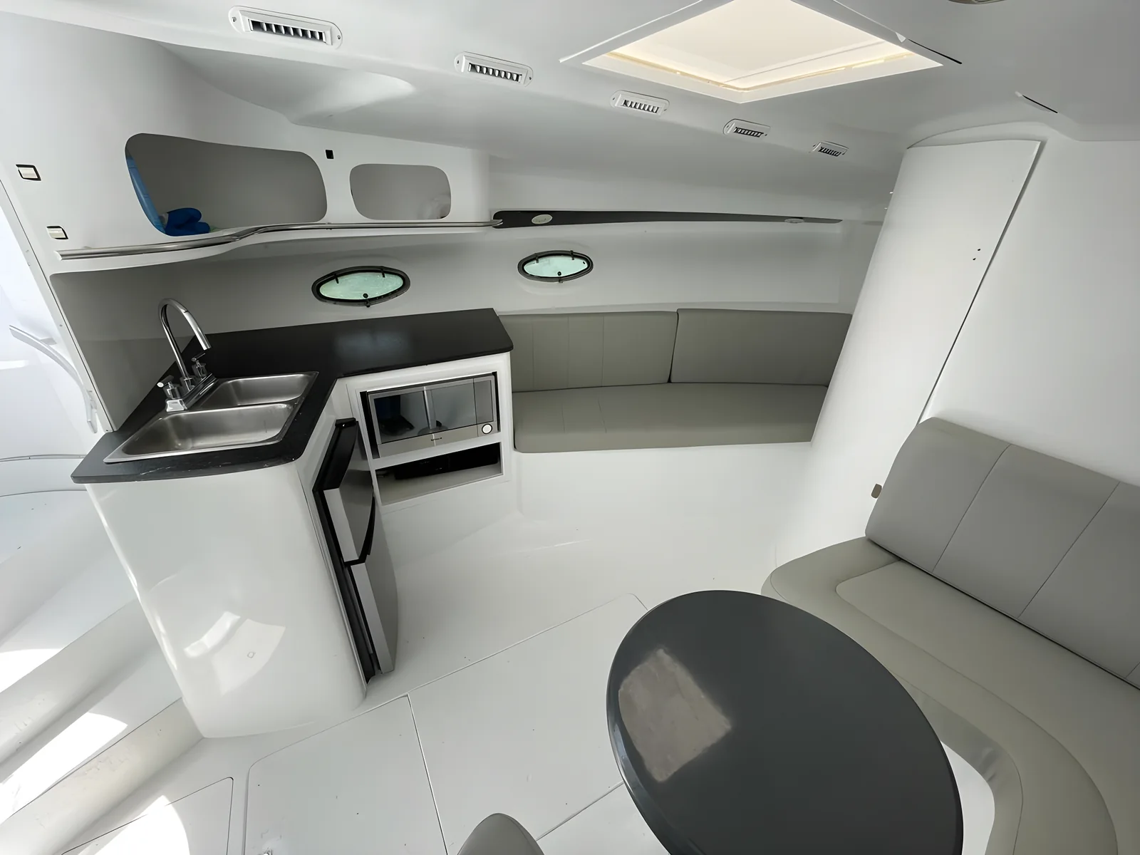 Salón interior del yate Blue Magic de 38 pies con asientos en L, mesa y cocina compacta.