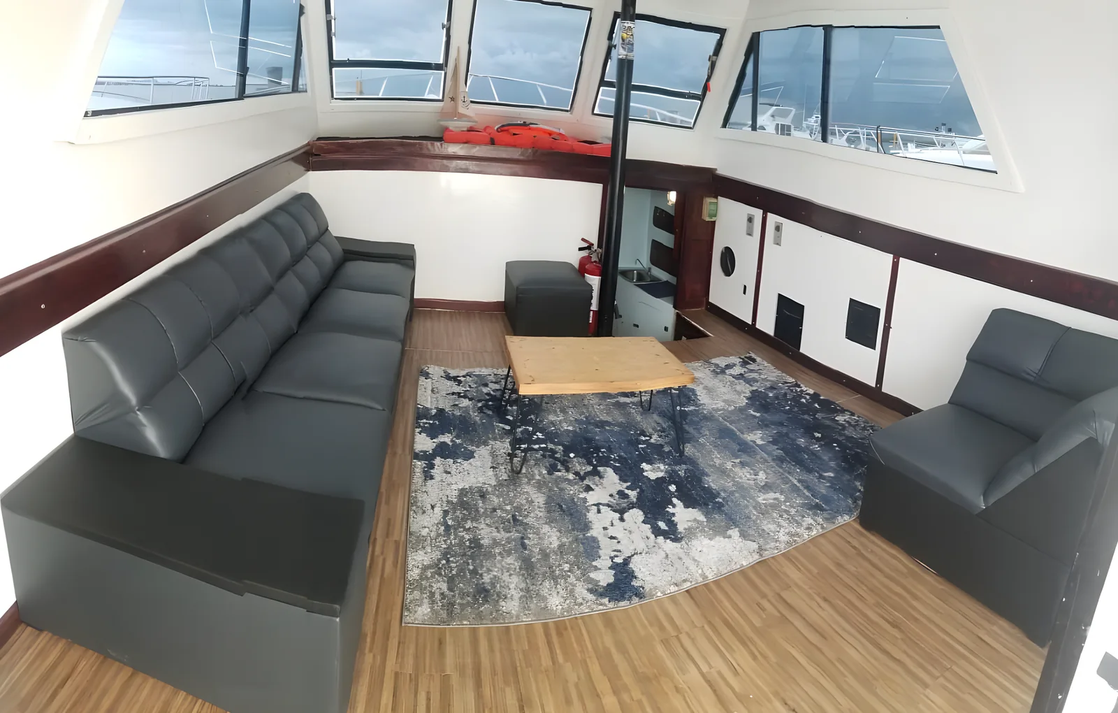 Interior del salón del yate Cap Ferrat con sofás grises y mesa de madera.