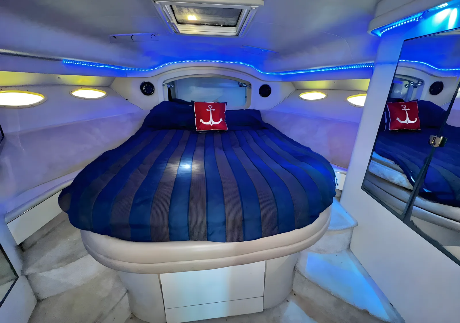 Cabina principal del yate Flycatcher de 46 pies con cama curva e iluminación azul.