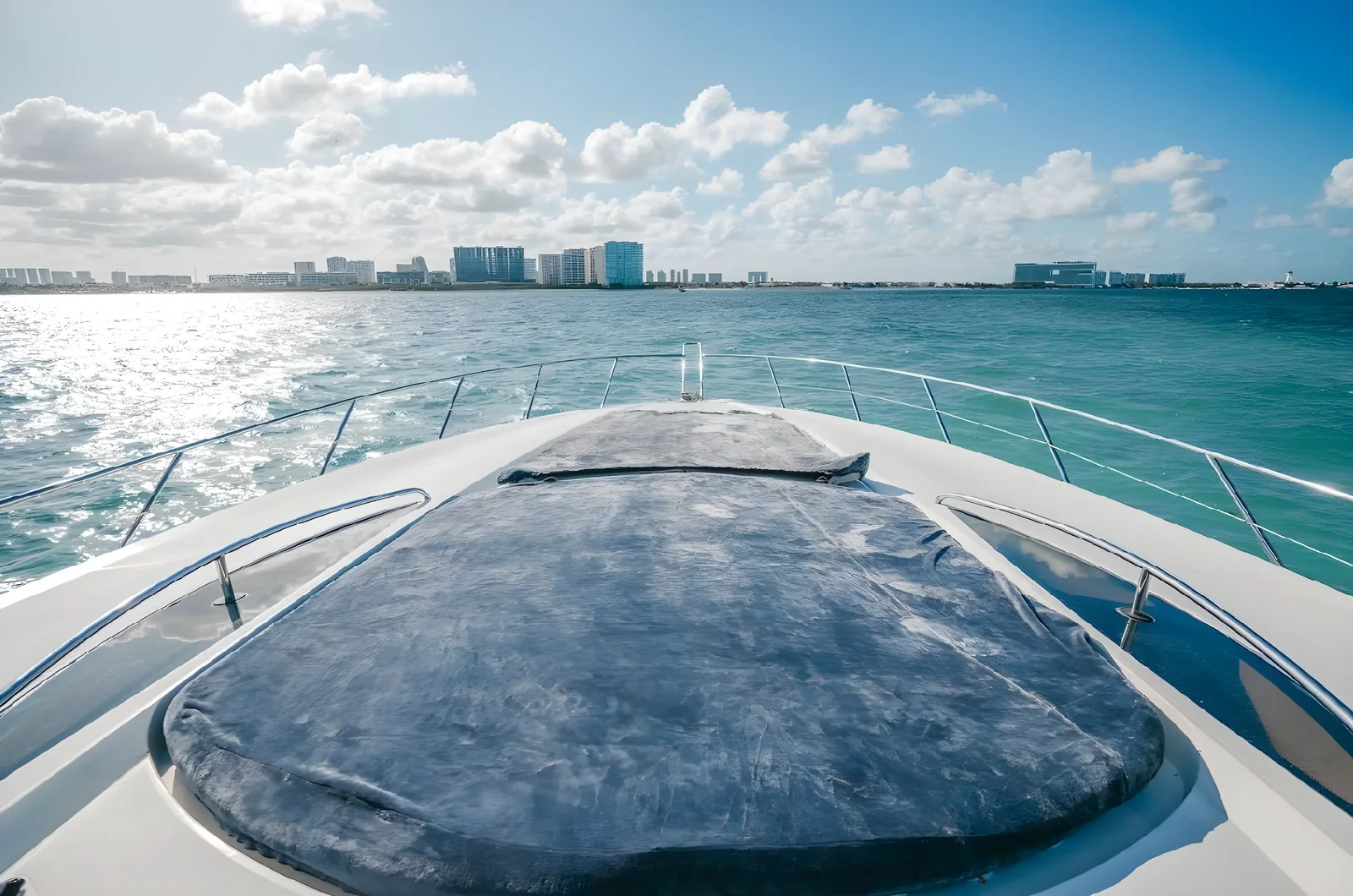 Proa del yate Gambler de 75 pies con colchoneta y horizonte costero al fondo.