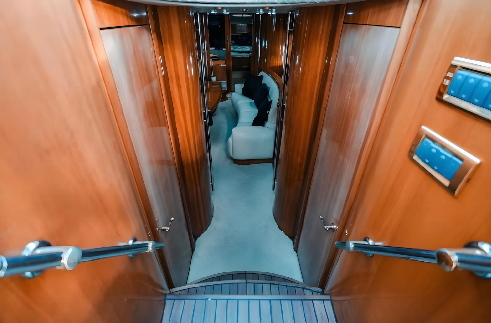 Pasillo interior del yate Gambler de 75 pies con barandillas, puertas de madera y vista al salón.
