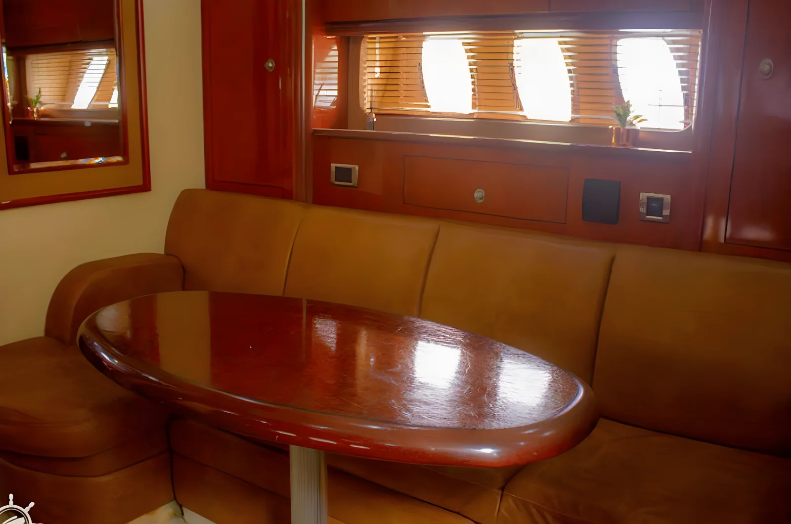 Rincón de comedor del yate Gypsea con sofá en U de cuero, mesa de madera y ventanas.