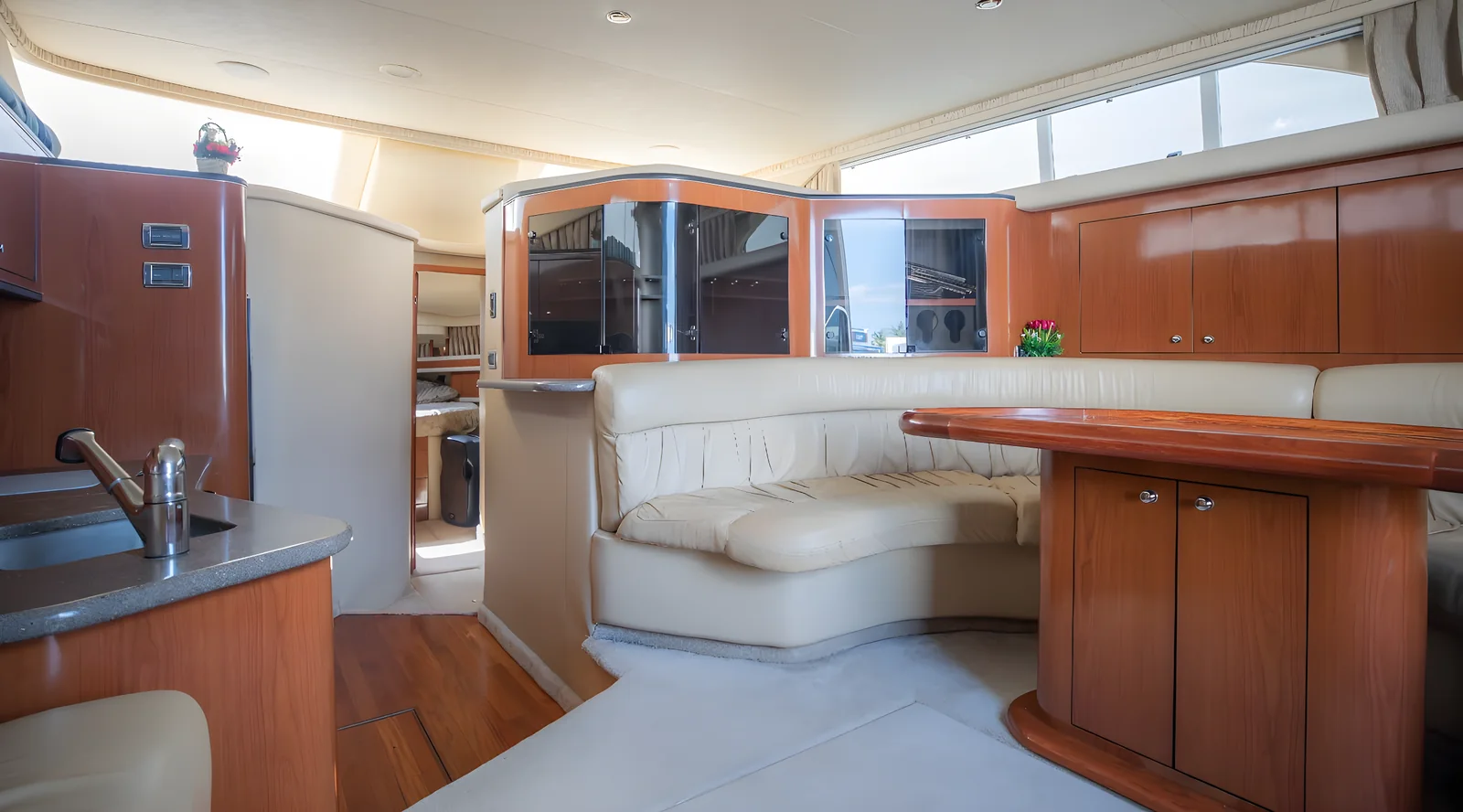 Salón interior del yate Hercules 46ft Fly con sofá curvo, mesa y acabados de madera.