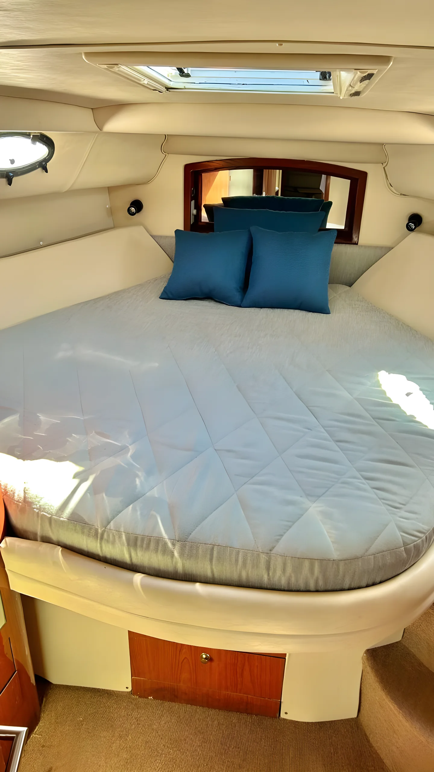 Cabina del yate Lady Liberty de 46 pies con cama, almohadas azules y claraboya.