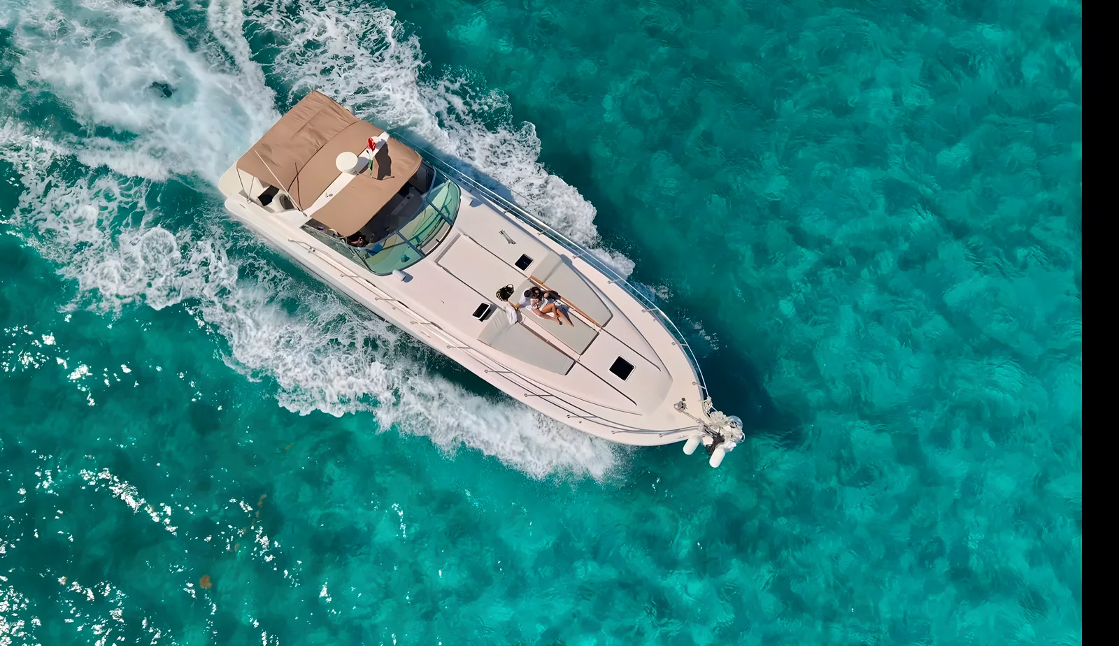 Vista aérea del yate Life Is Now de 50 pies navegando sobre aguas turquesa con huéspedes en la solarium de proa.