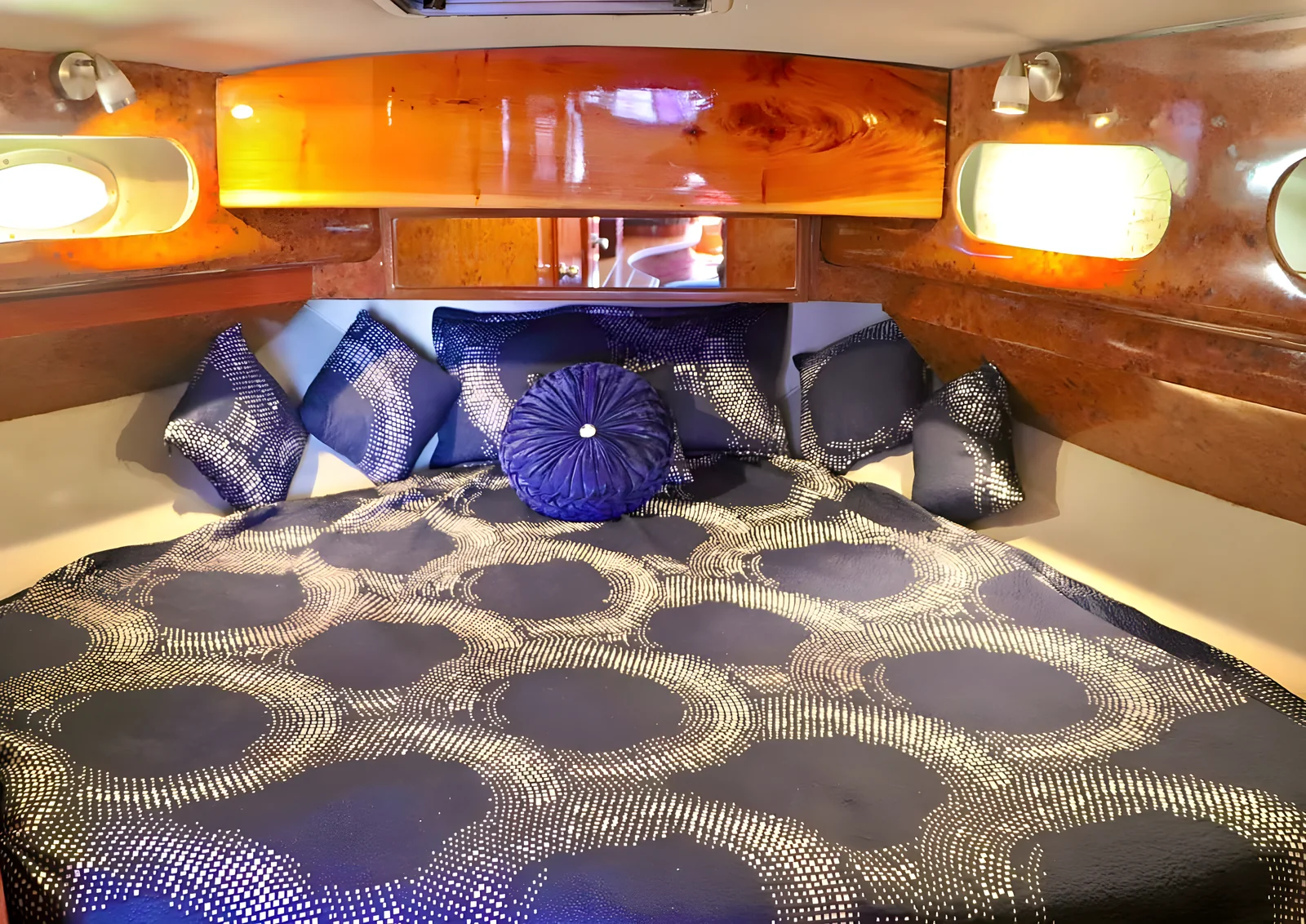 Cabina principal del yate Miss Cat con cama amplia, ropa de cama azul y acabados de madera.