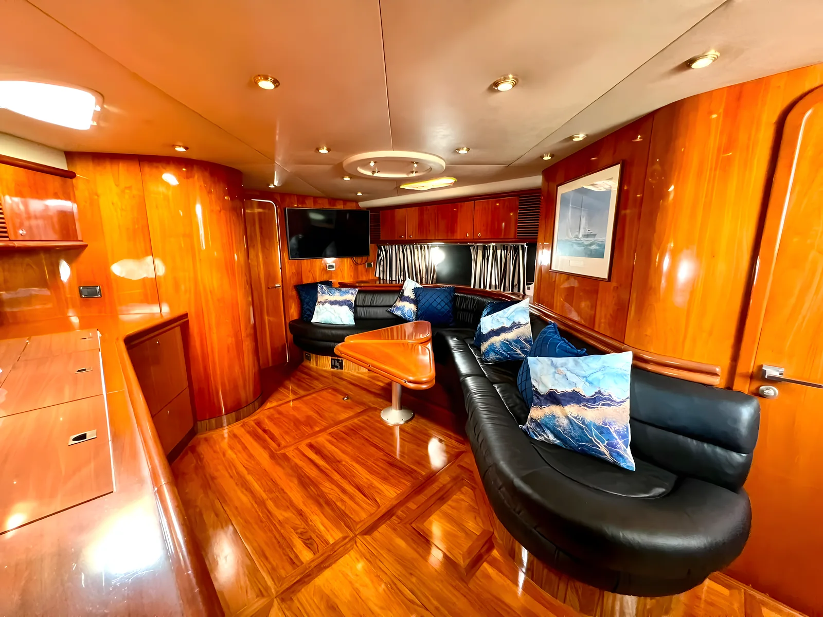 Salón interior del yate Pegasus de 60 pies con paneles de madera, sofá de cuero negro y mesa.