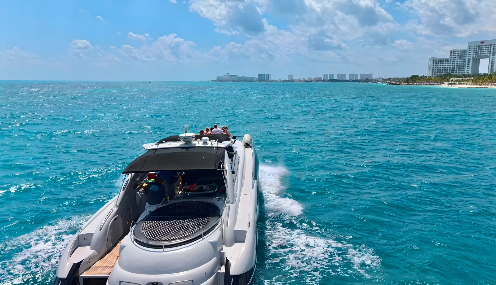 Vista de popa del yate Pegasus de 60 pies navegando con el horizonte costero al fondo.