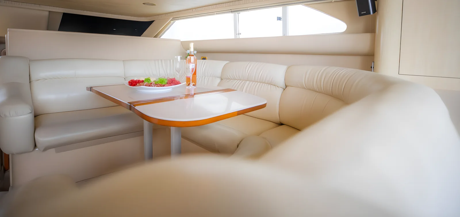 Vista interior del yate Polo Player con lounge tipo U y mesa preparada.