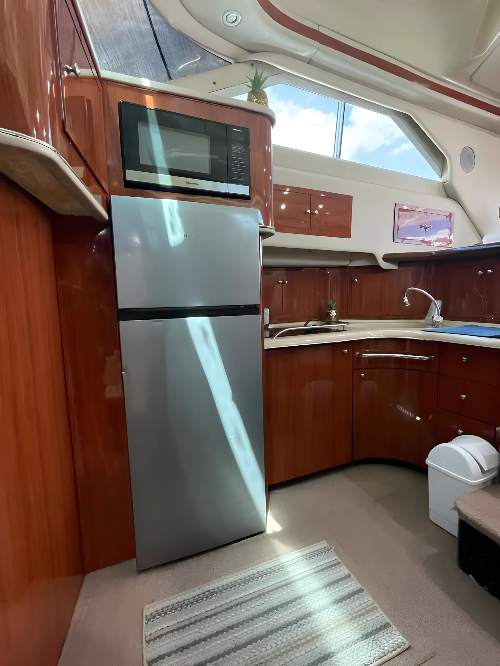 Cocina del yate University Drop Out con refrigerador, microondas, fregadero y armarios de madera.
