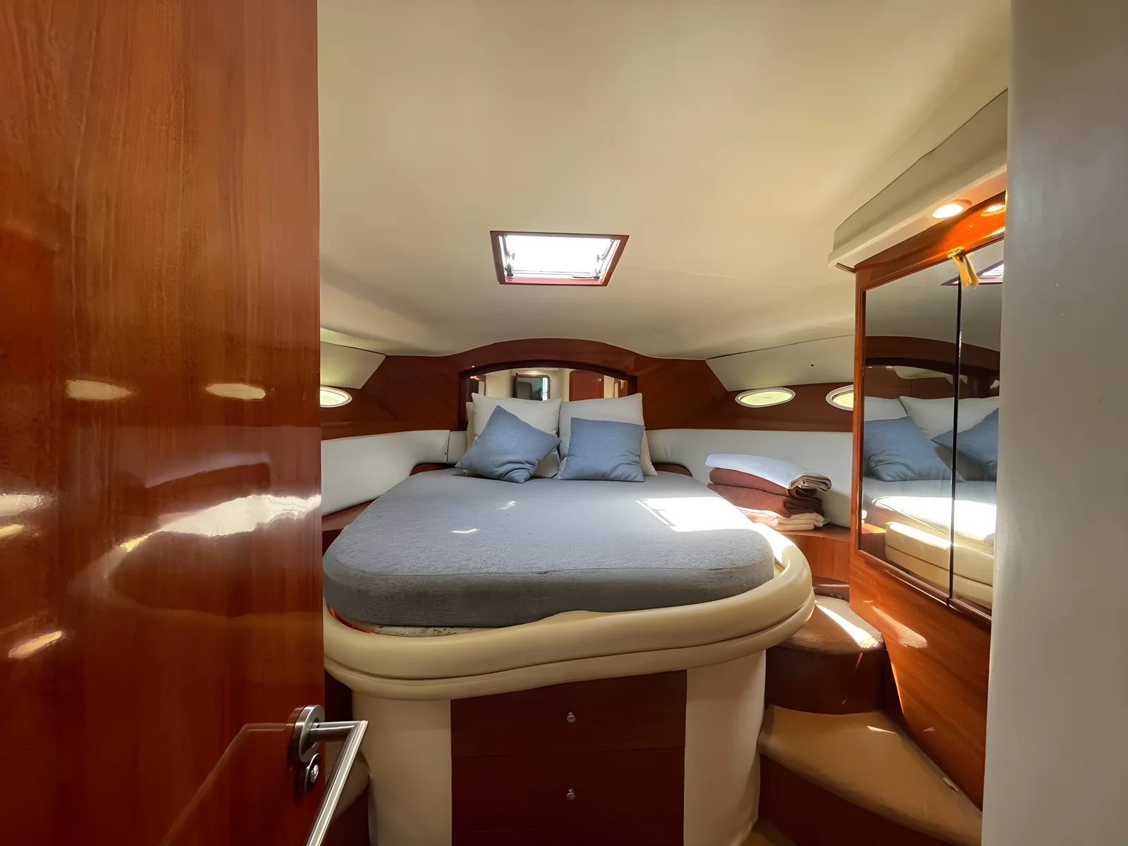 Cabina principal del yate University Drop Out con cama matrimonial, madera y espejos.